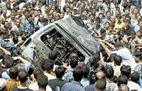 Palestinians roll the damaged car of senior Hamas leader Abdel-Aziz al-Rantissi after it was hit in an Israeli helicopter gunship attack in Gaza June 10, 2003. Israel tried to assassinate a leader of the Palestinian militant group Hamas on Tuesday, wounding al-Rantissi in a helicopter attack that could spur new violence and shatter a U.S.-backed peace plan.      REUTERS/Suhaib Salem
